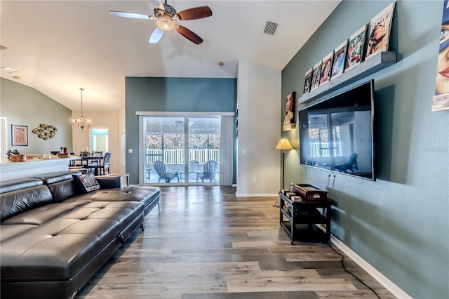 living room featuring lofted ceiling, ceiling fan with notable chandelier, and hardwood / wood-style floors