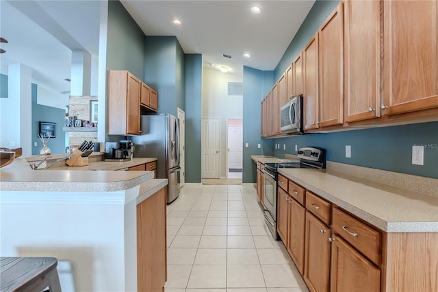 kitchen with light tile patterned flooring, a breakfast bar area, appliances with stainless steel finishes, and lofted ceiling