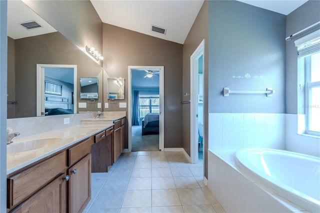 bathroom with vanity, vaulted ceiling, tile patterned floors, and a relaxing tiled tub