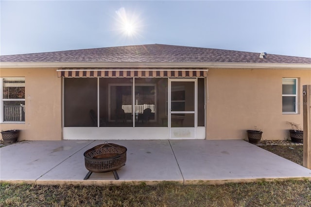 back of property with an outdoor fire pit, a patio, and a sunroom