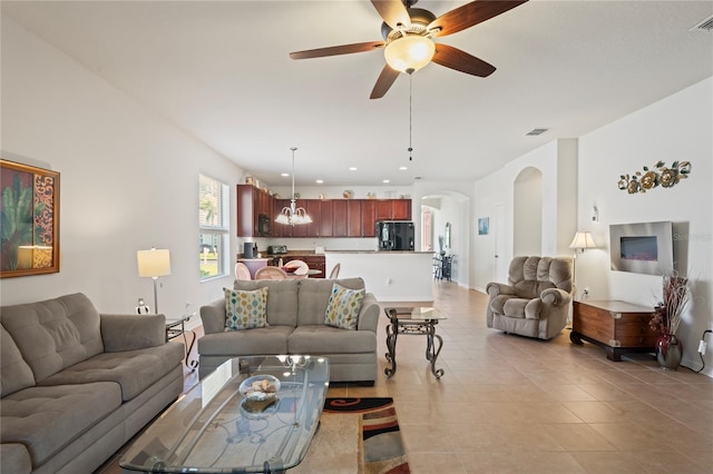 living room featuring light tile patterned floors and ceiling fan with notable chandelier