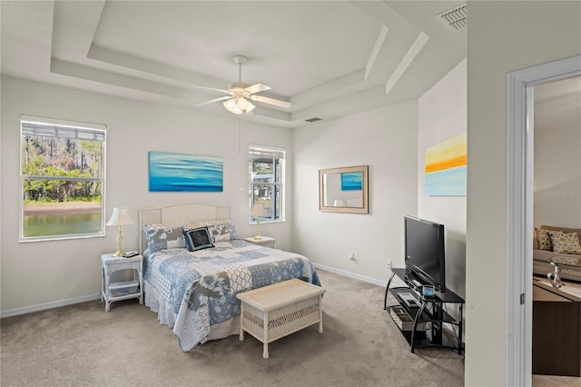 bedroom with ceiling fan, multiple windows, and a tray ceiling