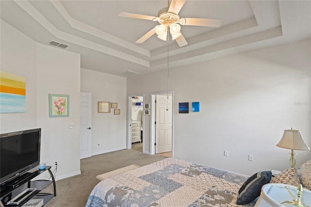 bedroom with ceiling fan, light colored carpet, a spacious closet, and a tray ceiling