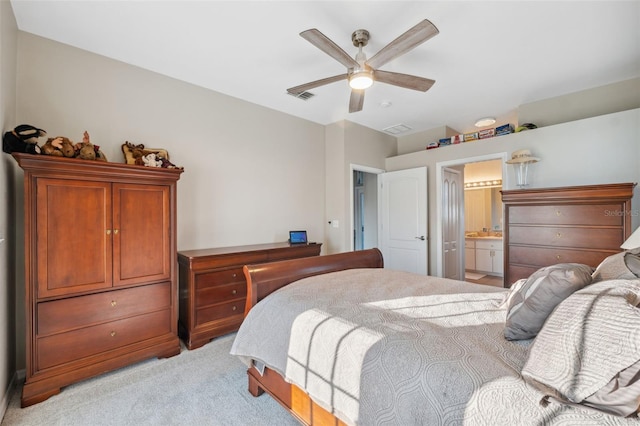 bedroom featuring ensuite bath, light colored carpet, and ceiling fan