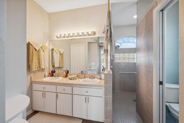 bathroom with toilet, a tile shower, and vanity