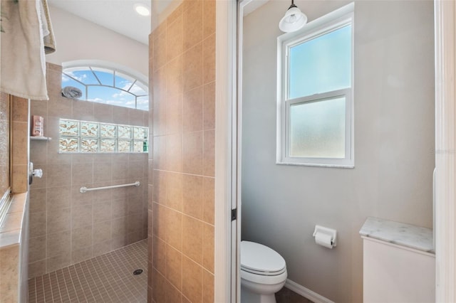 bathroom featuring a wealth of natural light, a tile shower, and toilet