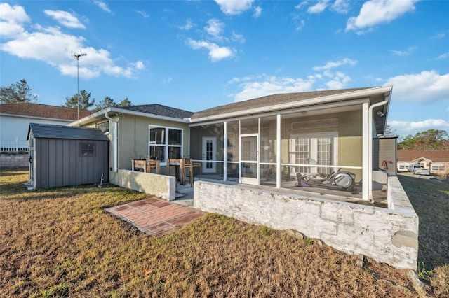 back of property featuring a patio area, a yard, a sunroom, and a storage shed