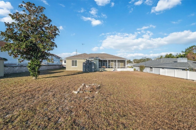 back of house with a sunroom, a storage shed, and a lawn