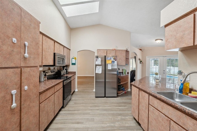 kitchen with stainless steel appliances, french doors, lofted ceiling with skylight, light wood-type flooring, and sink