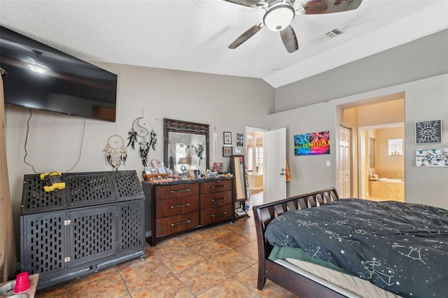 bedroom with ensuite bath, a textured ceiling, vaulted ceiling, tile patterned floors, and ceiling fan