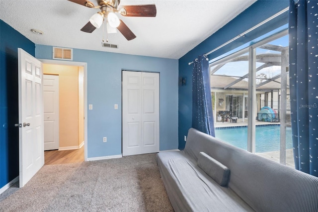 unfurnished room featuring a wealth of natural light, a textured ceiling, ceiling fan, and light carpet