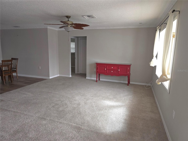 empty room featuring a textured ceiling, dark carpet, ceiling fan, and a healthy amount of sunlight