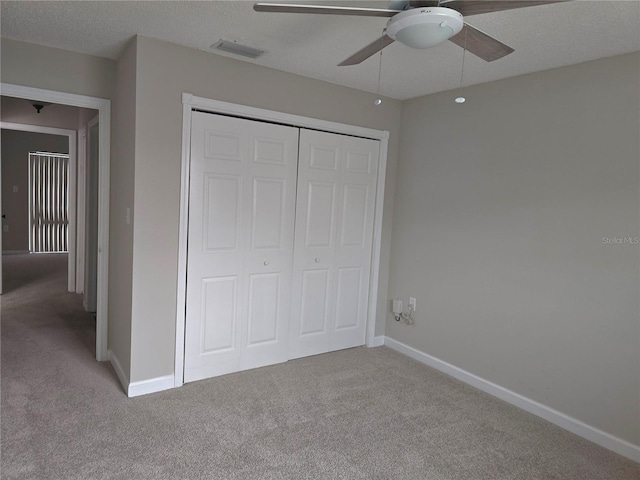 unfurnished bedroom featuring ceiling fan, a closet, carpet floors, and a textured ceiling