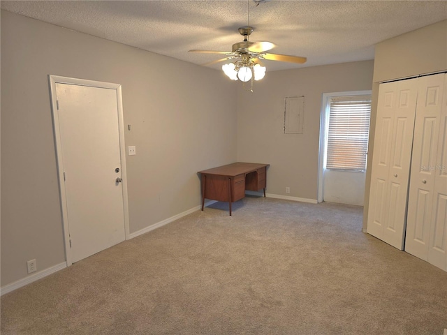 empty room with ceiling fan, light carpet, and a textured ceiling