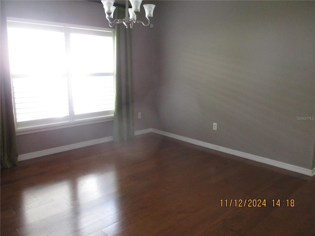 unfurnished room with dark hardwood / wood-style floors and a notable chandelier