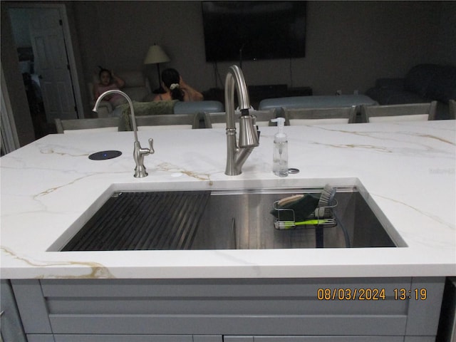 room details featuring gray cabinetry, light stone countertops, and sink