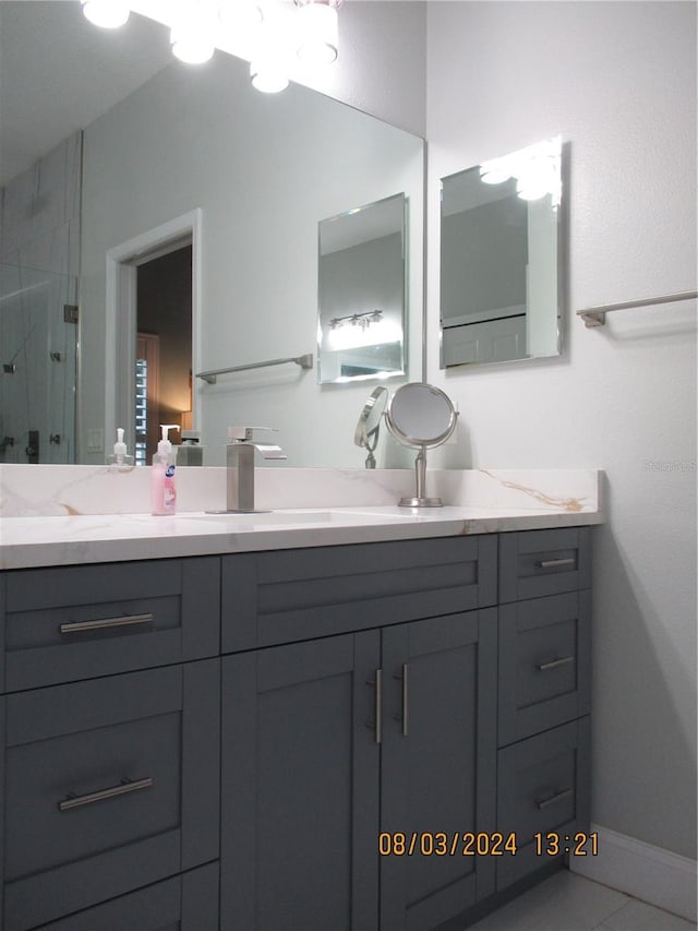 bathroom featuring tile patterned flooring, vanity, and walk in shower