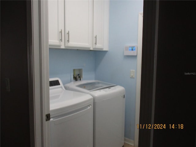 clothes washing area featuring cabinets and separate washer and dryer