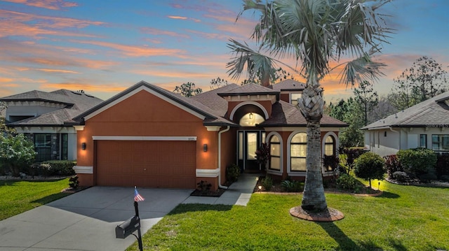 view of front facade with an attached garage, a shingled roof, stucco siding, a front lawn, and concrete driveway