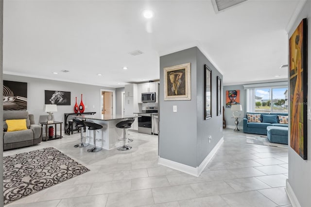 kitchen with a kitchen breakfast bar, appliances with stainless steel finishes, ornamental molding, a kitchen island, and white cabinets