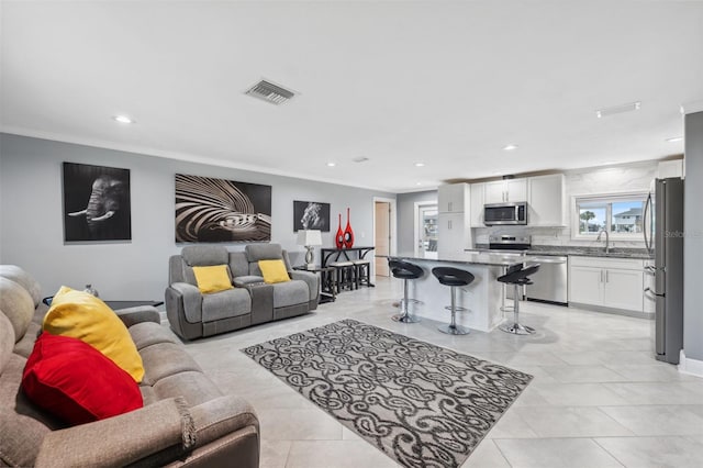 tiled living room with crown molding and sink