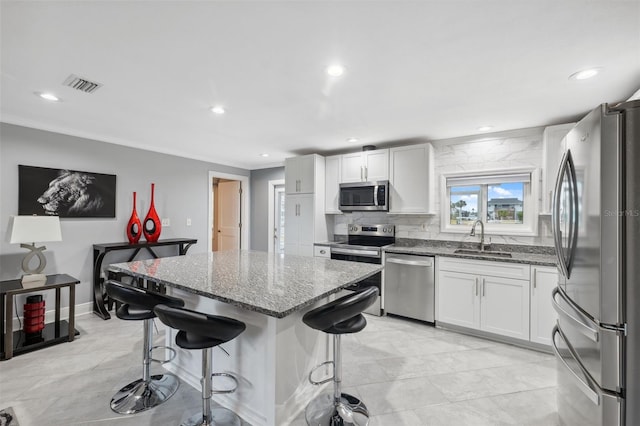 kitchen featuring appliances with stainless steel finishes, a kitchen breakfast bar, white cabinetry, and sink