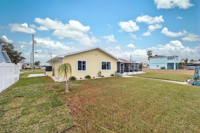 rear view of house with a lawn and a sunroom