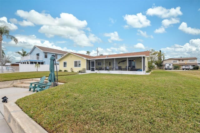 back of property with a patio, a sunroom, and a lawn