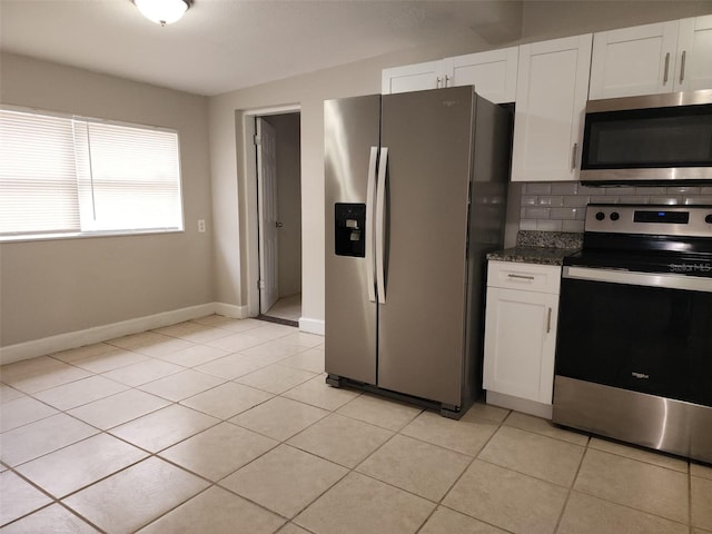 kitchen featuring dark stone counters, stainless steel appliances, white cabinetry, and light tile patterned floors