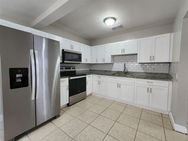 kitchen with dark stone countertops, appliances with stainless steel finishes, white cabinets, backsplash, and sink