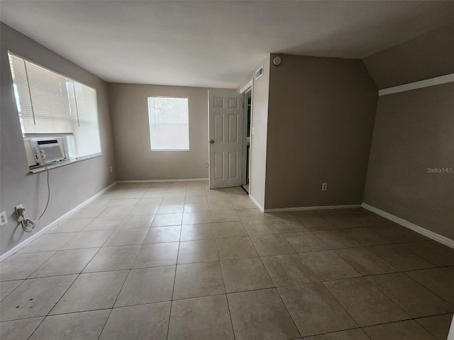 spare room featuring cooling unit, vaulted ceiling, and light tile patterned floors