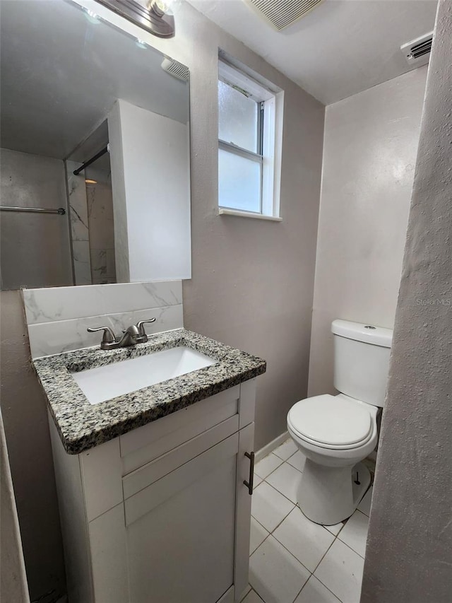 bathroom with toilet, tile patterned flooring, walk in shower, and vanity