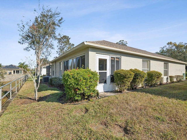 view of side of home featuring central AC and a lawn