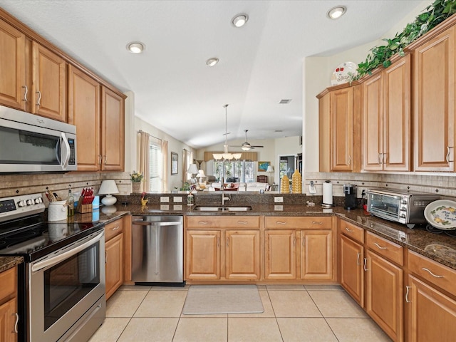 kitchen with tasteful backsplash, vaulted ceiling, dark stone counters, and appliances with stainless steel finishes