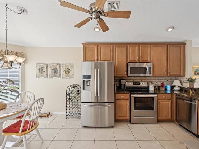 kitchen featuring ceiling fan with notable chandelier, pendant lighting, decorative backsplash, light tile patterned floors, and stainless steel appliances