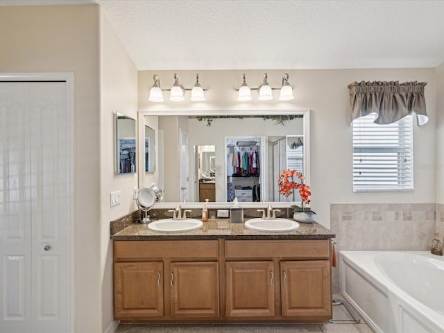 bathroom with tile patterned flooring, a textured ceiling, a washtub, and vanity