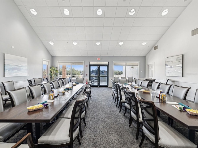 carpeted dining room featuring french doors and high vaulted ceiling