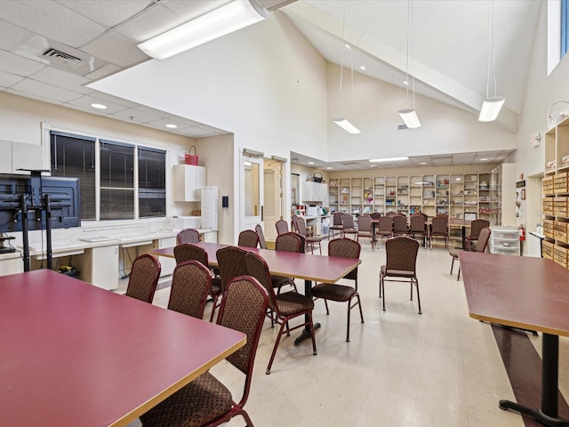 dining space featuring a drop ceiling and a high ceiling