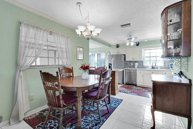 dining room featuring ceiling fan with notable chandelier, a textured ceiling, sink, and a healthy amount of sunlight