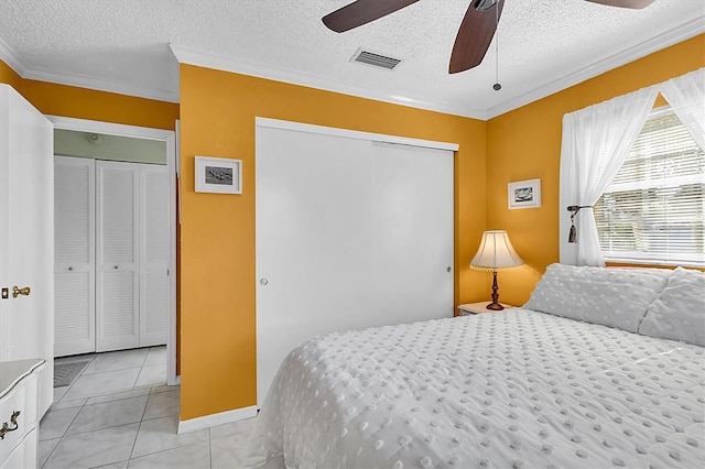 bedroom featuring a textured ceiling, ceiling fan, light tile patterned floors, and a closet