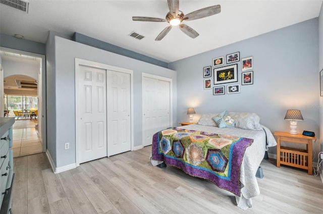 bedroom with two closets, ceiling fan, and light hardwood / wood-style flooring