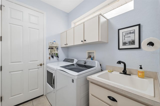 clothes washing area with cabinets, light tile patterned floors, washer and clothes dryer, and sink