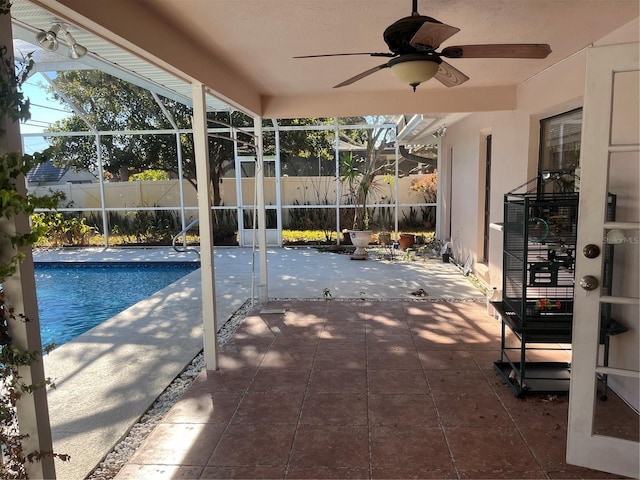 view of swimming pool with glass enclosure, ceiling fan, and a patio area