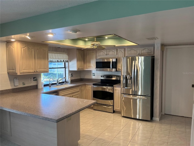 kitchen with kitchen peninsula, stainless steel appliances, ceiling fan, sink, and light tile patterned flooring