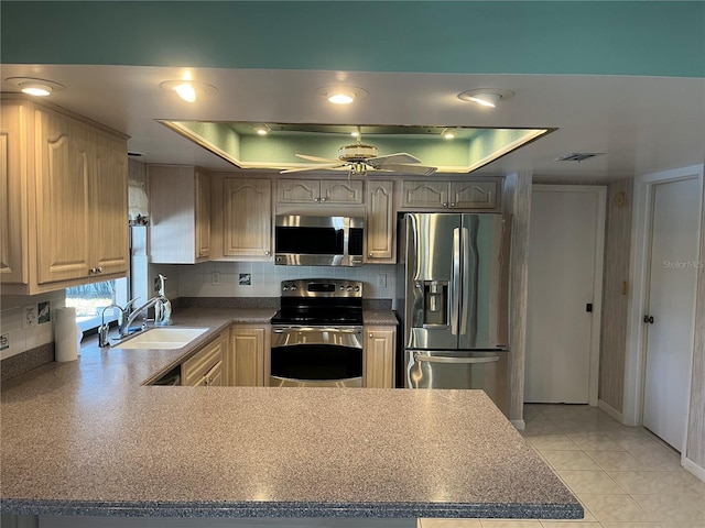 kitchen with ceiling fan, sink, stainless steel appliances, a raised ceiling, and light tile patterned flooring