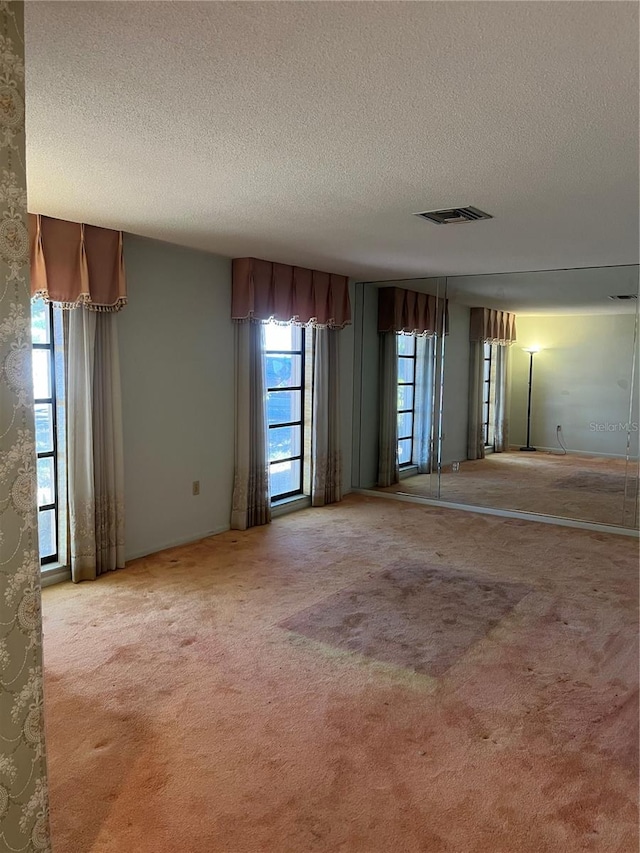 empty room with light colored carpet and a textured ceiling