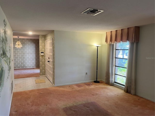 spare room with light colored carpet and an inviting chandelier