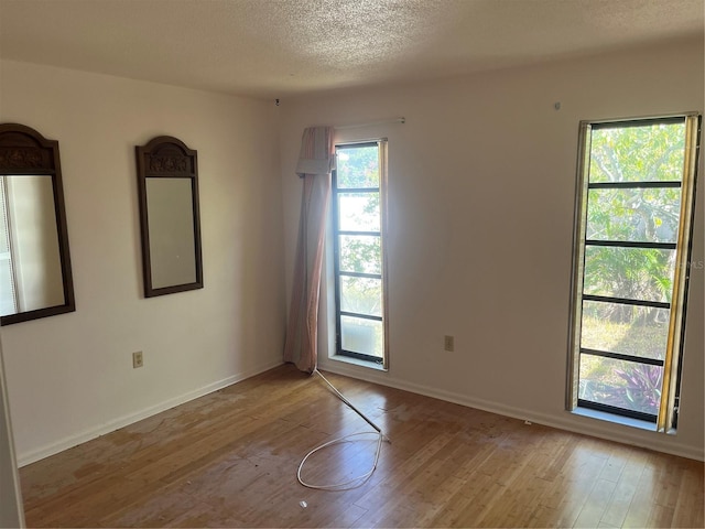 spare room featuring light hardwood / wood-style floors and a textured ceiling