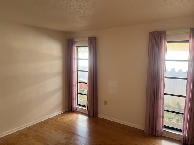 empty room featuring hardwood / wood-style flooring, a healthy amount of sunlight, and a textured ceiling