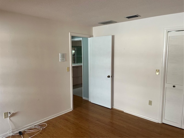 spare room with dark wood-type flooring and a textured ceiling